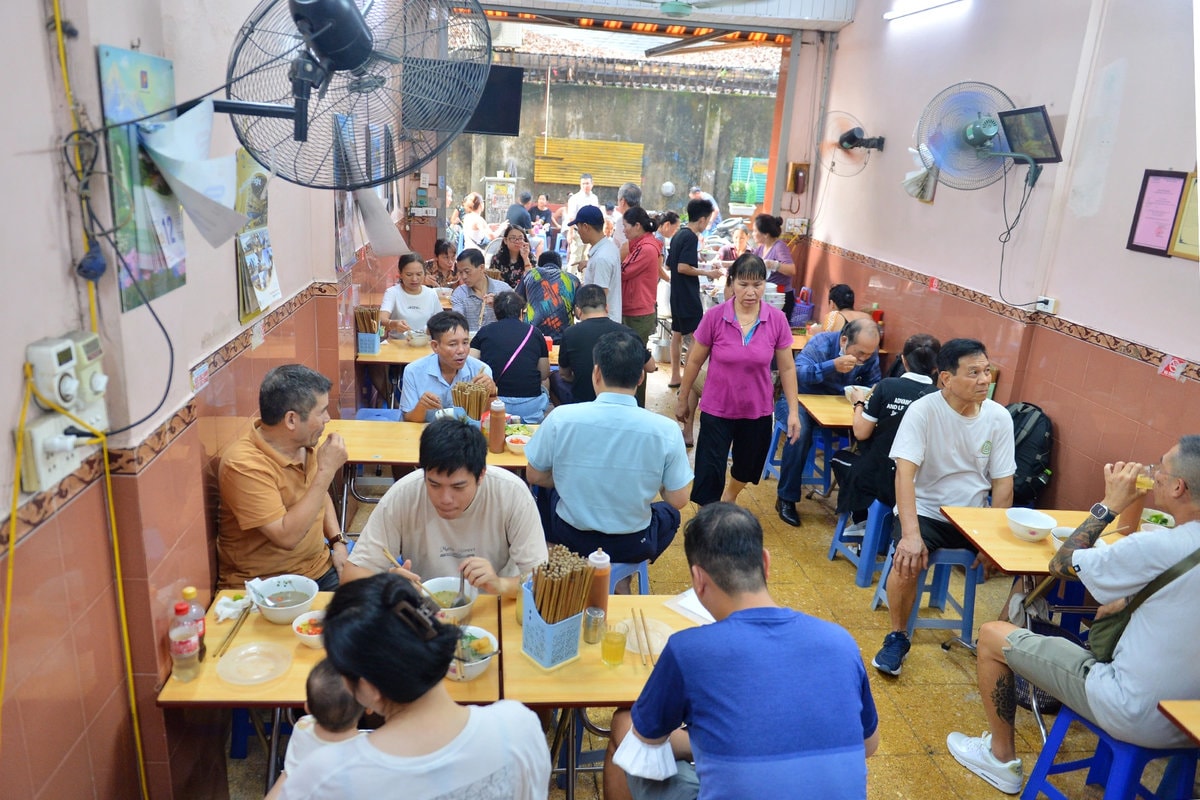 Local Vietnamese family enjoying affordable street food dinner on plastic stools outside a traditional eatery 